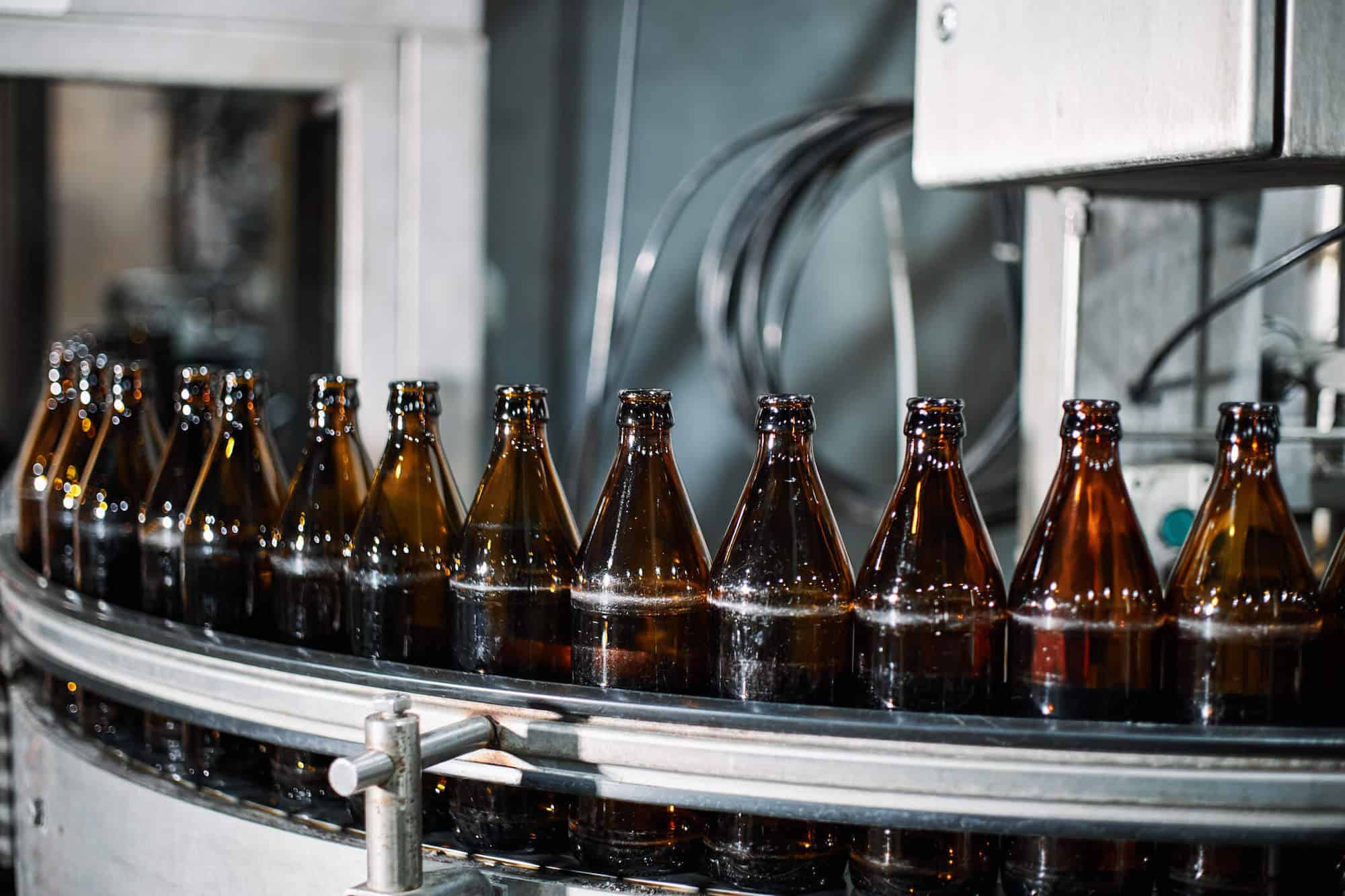 bottles lined up on a bottling machine in a factory