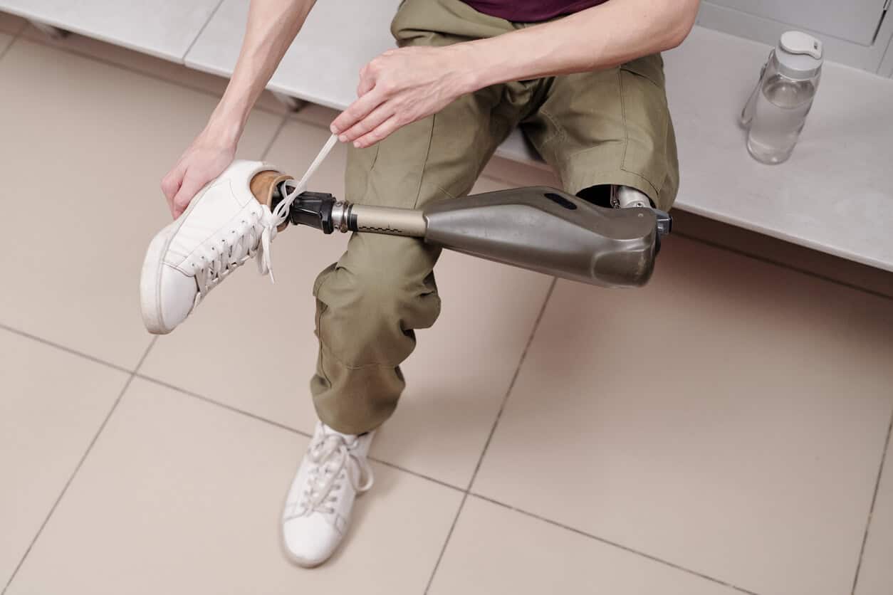 Man with robotic leg putting sports shoes while preparing for training